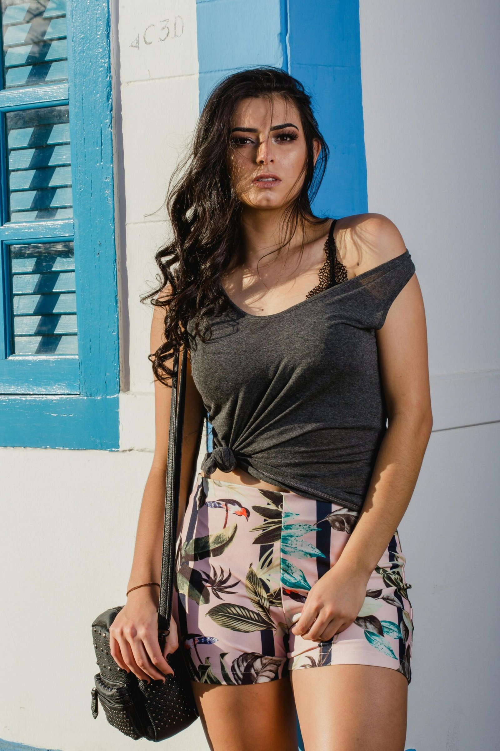 Stylish woman posing outdoors in a casual summer outfit with vibrant colors.